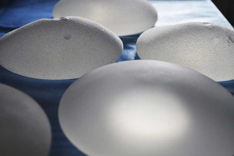 Several textured silicone breast implants resting on a blue sterile drape